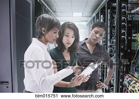Stock Image - Businesswomen working together in server room. Fotosearch