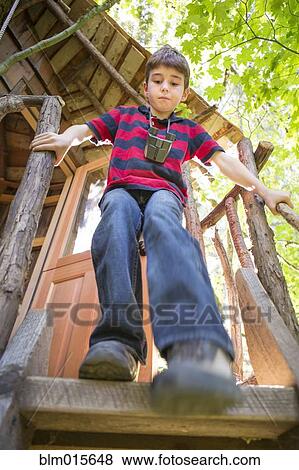 Stock Photo - Caucasian boy climbing down from tree house. Fotosearch