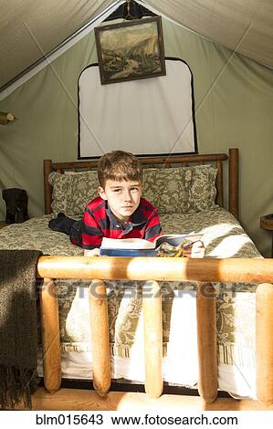 Stock Image - Caucasian boy laying in bed in tent. Fotosearch