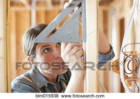 Caucasian carpenter measuring wall in unfinished room View Large Photo Image Stock Photo - Caucasian carpenter measuring wall in unfinished room. Fotosearch