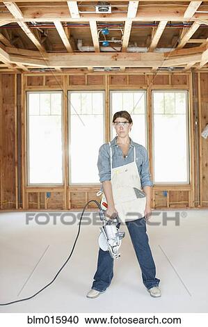 Caucasian construction worker standing in unfinished room with saw View Large Photo Image Stock Image - Caucasian construction worker standing in unfinished room with saw. Fotosearch