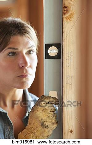 Stock Image - Caucasian construction worker using level. Fotosearch