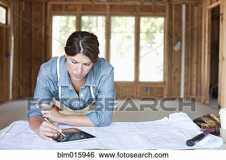 Caucasian construction worker using digital tablet in unfinished room View Large Photo Image Stock Photograph - Caucasian construction worker using digital tablet in unfinished room. Fotosearch