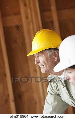 Picture - Caucasian construction workers in unfinished room. Fotosearch