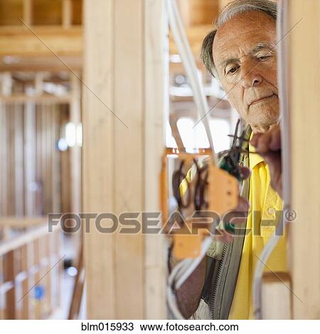 Caucasian electrician working on wiring in unfinished room View Large Photo Image Stock Image - Caucasian electrician working on wiring in unfinished room. Fotosearch