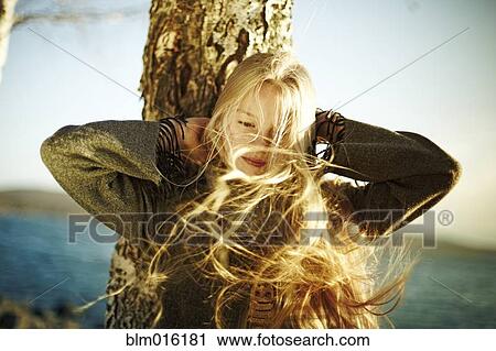 Stock Image - Caucasian girl's hair being blown by the wind near ocean. Fotosearch