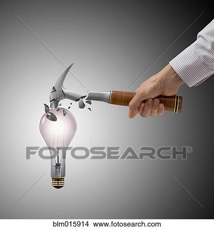 Picture - Caucasian man breaking hammer on light bulb. Fotosearch