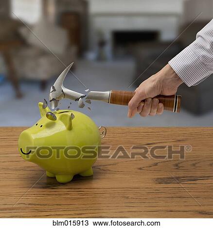 Stock Image - Caucasian man smashing piggy bank. Fotosearch
