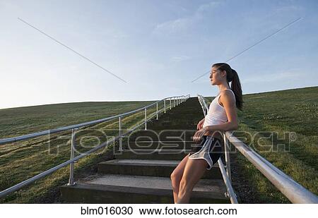 Stock Image - Caucasian runner leaning on staircase railing. Fotosearch