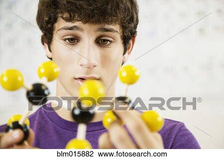 Stock Image - Caucasian student looking at chemistry model. Fotosearch
