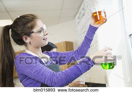Stock Image - Caucasian student working with chemicals in classroom. Fotosearch