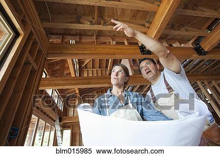 Construction workers looking at blueprints in unfinished room View Large Photo Image Stock Photography - Construction workers looking at blueprints in unfinished room. Fotosearch