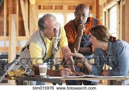 Stock Photograph - Construction workers talking in unfinished room. Fotosearch