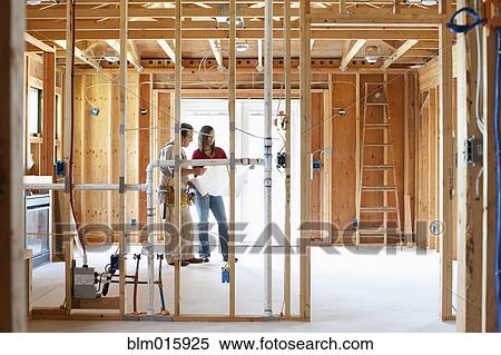 Stock Photography - Construction workers working in unfinished room. Fotosearch