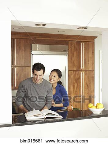 Stock Image - Couple cooking together in kitchen. Fotosearch