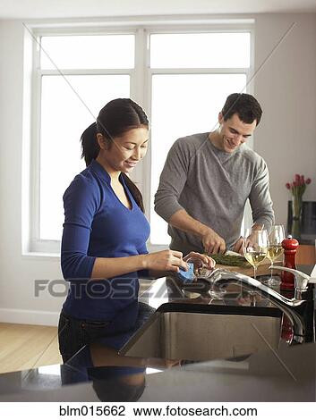 Stock Image - Couple cooking together in kitchen. Fotosearch