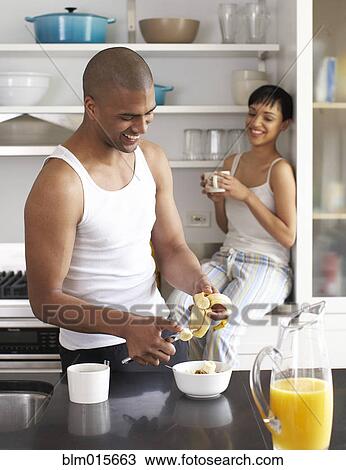 Stock Image - Couple eating breakfast in kitchen. Fotosearch
