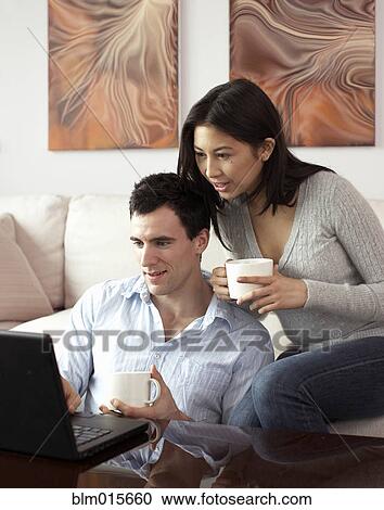 Stock Image - Couple looking at laptop together. Fotosearch