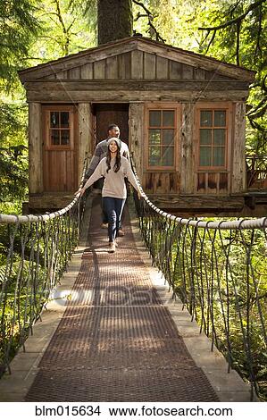 Picture - Couple on walkway of remote tree house. Fotosearch