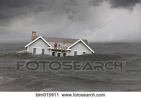Stock Image - Family sitting on roof of house floating in sea. Fotosearch