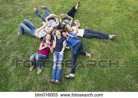 Stock Image - Friends hanging out together on grass. Fotosearch