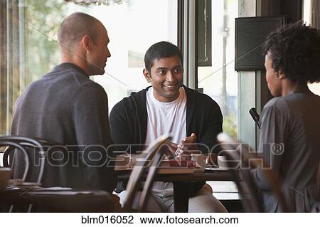Stock Image - Friends sitting together in cafe. Fotosearch