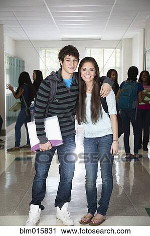 Stock Image - High school friends standing in corridor together. Fotosearch