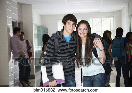 Stock Image - High school friends standing in corridor together. Fotosearch