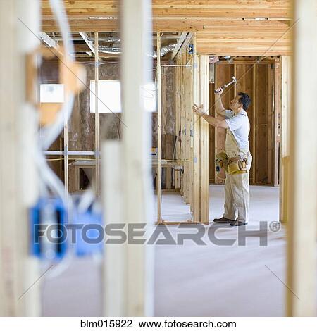 Stock Image - Hispanic carpenter building wall frame. Fotosearch