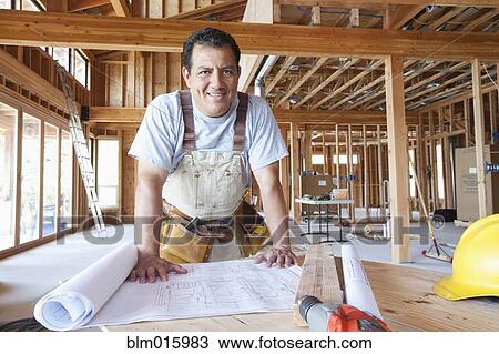 Hispanic construction worker looking at blueprints in unfinished room View Large Photo Image Stock Image - Hispanic construction worker looking at blueprints in unfinished room. Fotosearch