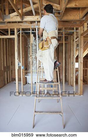 Hispanic construction worker on ladder in unfinished room View Large Photo Image Stock Photo - Hispanic construction worker on ladder in unfinished room. Fotosearch