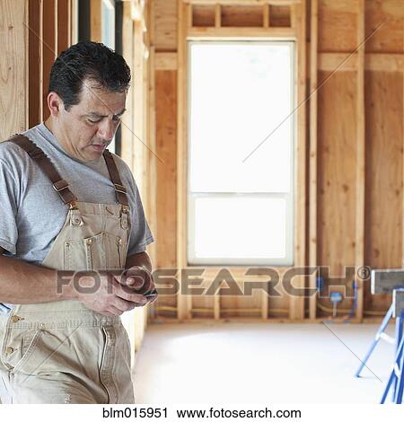 Hispanic construction worker text messaging on cell phone in unfinished room View Large Photo Image Stock Image - Hispanic construction worker text messaging on cell phone in unfinished room. Fotosearch