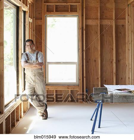 Stock Photo - Hispanic construction worker with arms crossed in unfinished room. Fotosearch