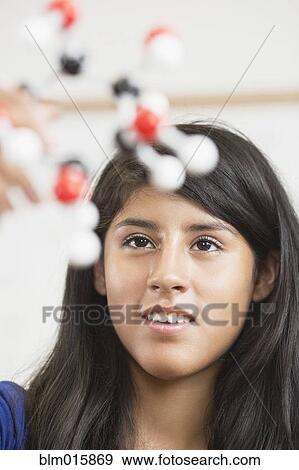 Stock Photo - Hispanic student examining chemistry model in classroom. Fotosearch