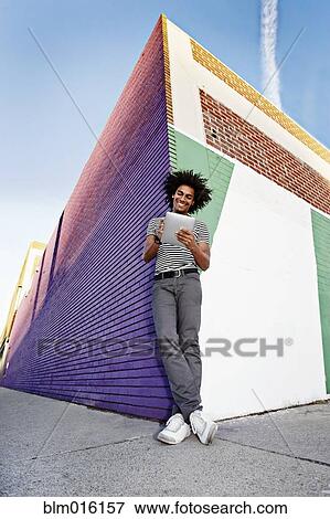 Man using digital tablet and leaning on wall outdoors View Large Photo Image Stock Photo - Man using digital tablet and leaning on wall outdoors. Fotosearch