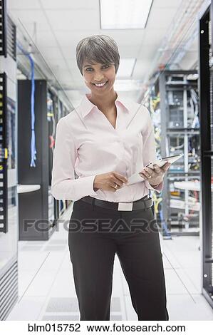 Stock Image - Mixed race businesswoman in server room. Fotosearch