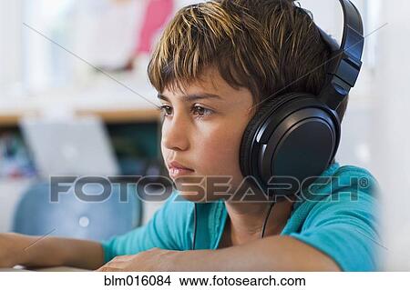 Mixed race student listening to headphones in classroom View Large Photo Image Picture - Mixed race student listening to headphones in classroom. Fotosearch