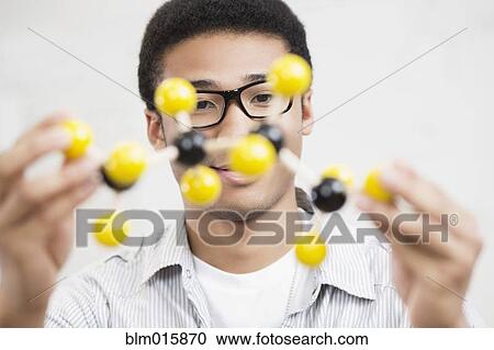 Stock Image - Mixed race teenager holding chemistry model. Fotosearch