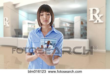 Stock Image - Mixed race woman using digital tablet in pharmacy. Fotosearch