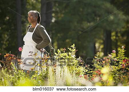 Stock Photo - Mixed race woman wearing apron in field. Fotosearch