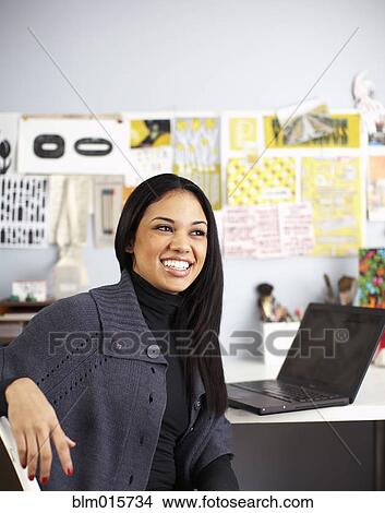 Smiling businesswoman sitting at desk View Large Photo Image Picture - Smiling businesswoman sitting at desk. Fotosearch