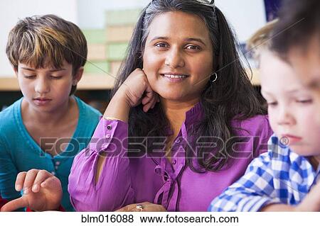 Stock Photo - Smiling teacher with students in classroom. Fotosearch