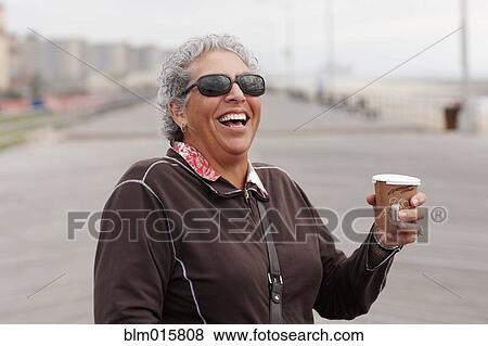 Smiling woman drinking coffee on boardwalk View Large Photo Image Stock Photo - Smiling woman drinking coffee on boardwalk. Fotosearch