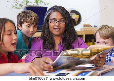 Stock Photo - Teacher reading book to students in classroom. Fotosearch