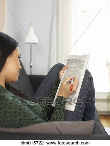Stock Image - Woman reading classified ads in newspaper. Fotosearch