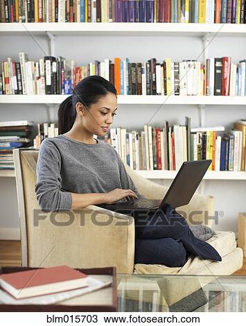 Stock Image - Woman sitting in chair using laptop. Fotosearch