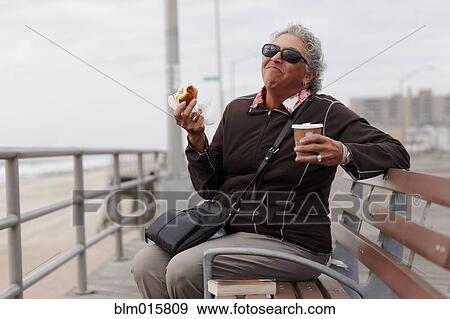 Stock Photo - Women eating pastry and drinking coffee on boardwalk. Fotosearch