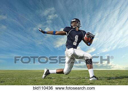 Stock Photograph - African American football player poised on field. Fotosearch