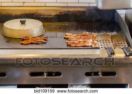 Stock Photo - Bacon on griddle in restaurant. Fotosearch