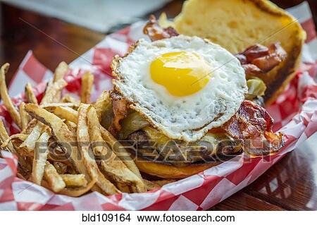Picture - Basket of french fries with cheeseburger and egg. Fotosearch